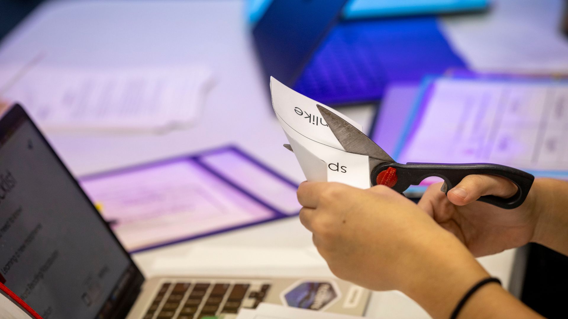 Student teacher cutting paper in elementary classroom