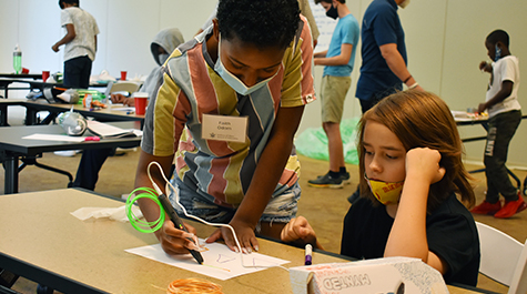 A mentor and camper construct fins for the bottle rocket using a 3D pen.