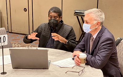 Lavare Henry Ph.D. '23 (left) discusses his research approach at the roundtable session.